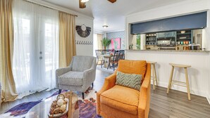 Ein Wohnzimmer mit Deckenventilator, ein Essbereich mit Tisch und Stühlen sowie eine Küche mit Arbeitsfläche und Geräten.