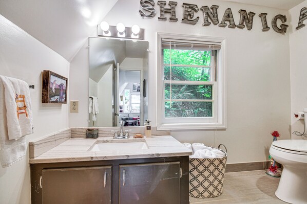 A bathroom with a vanity, sink, mirror, and a window with a view of greenery. - Waterfront Lake Lure A-Frame w/ Dock & Scenic Deck (Lake Lure)
