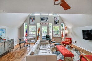 Ein geräumiges Loft mit Essbereich, einer großen Couch und einem Fernseher.