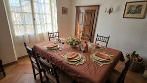 Een eetkamer met een tafel voor vier personen, met een bruine tafelkleed, houten stoelen en een bloevas.