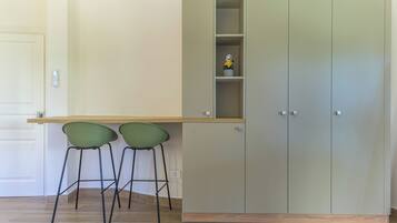 A kitchenette with a built-in cabinet, two green chairs, and a small shelf with a figurine.