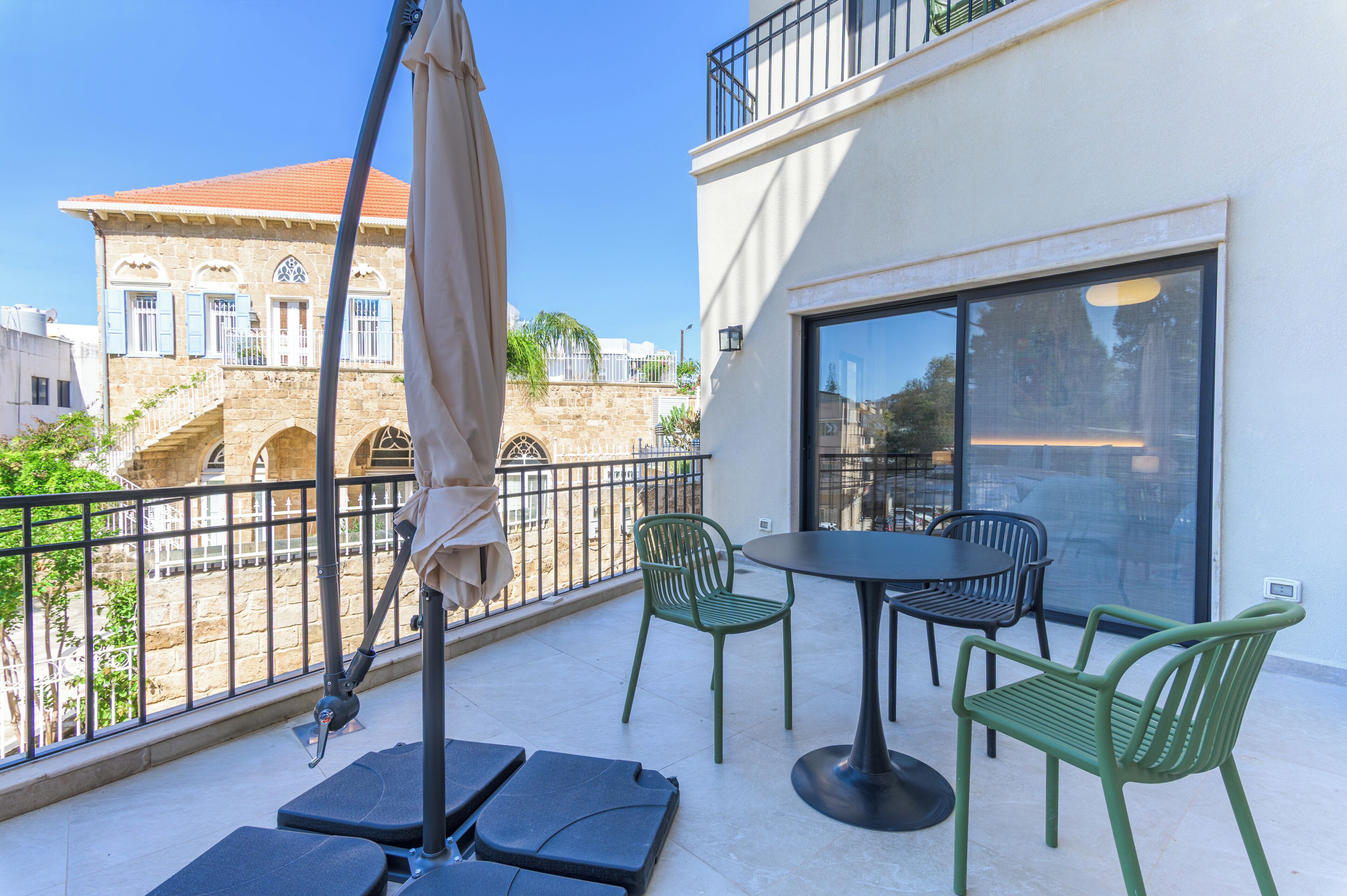 A balcony with a table and chairs, a pergola, and a view of a historic building.