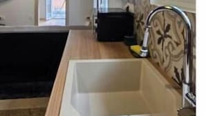 A modern kitchen with a large sink, a window, and a built-in oven. - Zante Cozy Apartment (Zakinthos)