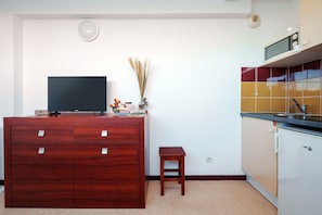 A compact kitchen with a microwave, a small table, and a TV on a wooden cabinet. - Saint Clair N°318 - ST3 (Agde)
