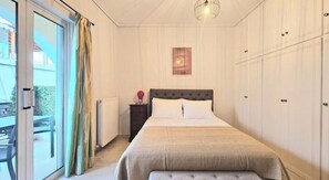 A bedroom with a bed, a nightstand, a lamp, and a view of the outside. - Andreas Luxurious Central Living (2 BD, 2WC) (Zakinthos)
