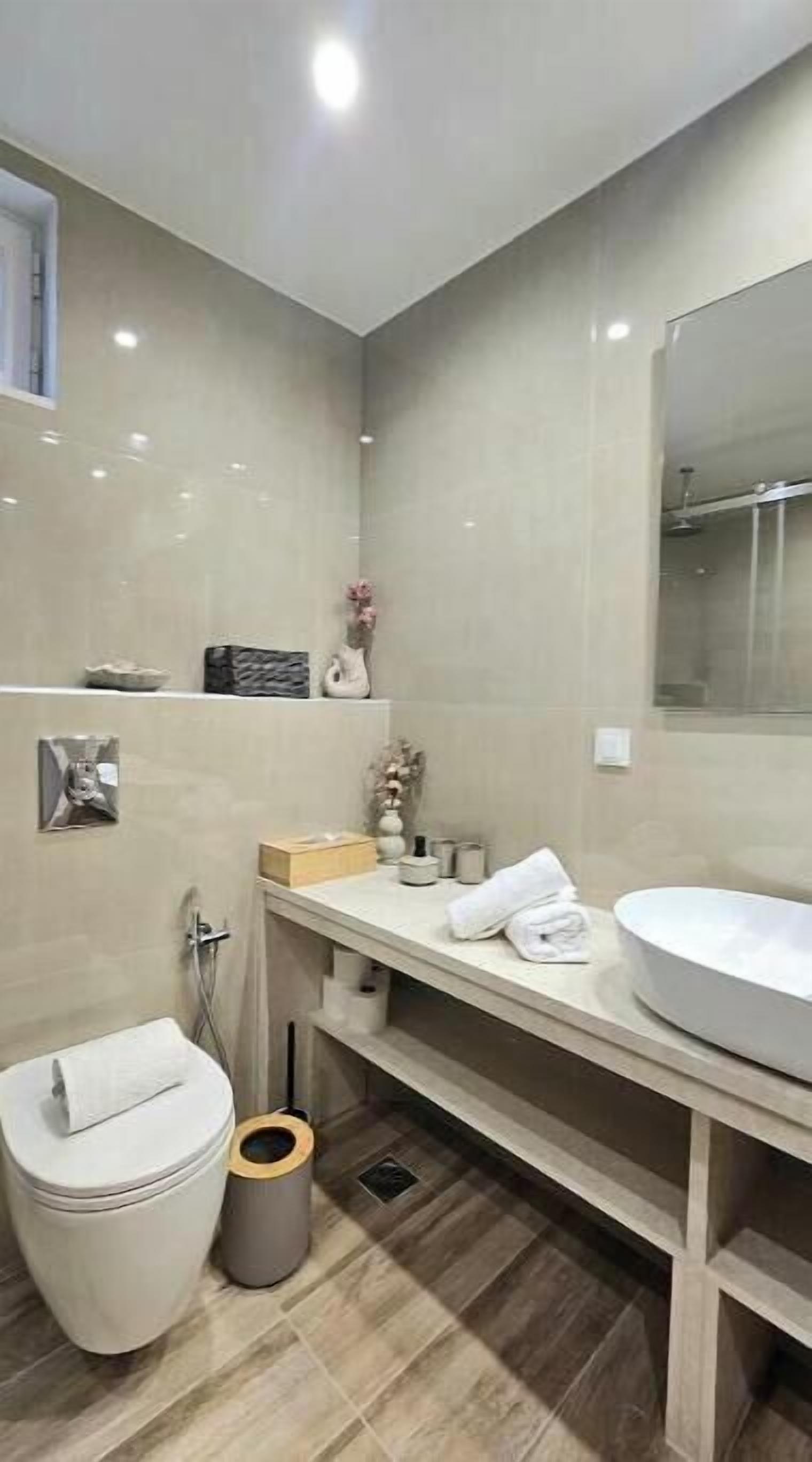 A modern bathroom with a toilet, bidet, sink, and mirror.