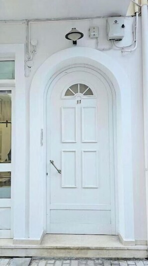 A white door with a semi-circular arch above it, a small window with a grid pattern, and a doorbell above the door. - Andreas Luxurious Central Living (2 BD, 2WC) (Zakinthos)