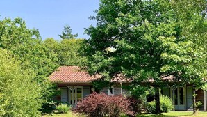 A house with a red-tiled roof, surrounded by lush greenery and trees. - Nature Cottage Near Puy du Fou (Moutiers-Sous-Chantemerle)