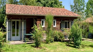 A wooden house with a tiled roof, a covered porch, and a small garden. - Nature Cottage Near Puy du Fou (Moutiers-Sous-Chantemerle)
