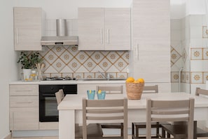Una cocina moderna con armarios de madera clara, una estufa a gas y un comedor con dos sillas.