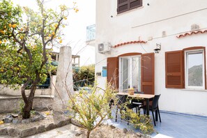 A building with a balcony, a table with chairs, and a tree with fruit. - Villa Comar (Forio)