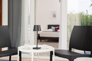 A hotel room with a bed, a table with a lamp, and two chairs. - Villa Comar (Forio)
