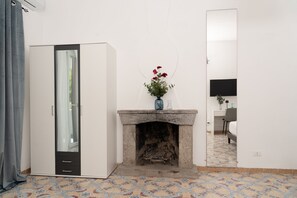 Ein Zimmer mit Schrank, Kamin, einer Blumenvase, Schreibtisch und Stuhl sowie einem Fernseher.