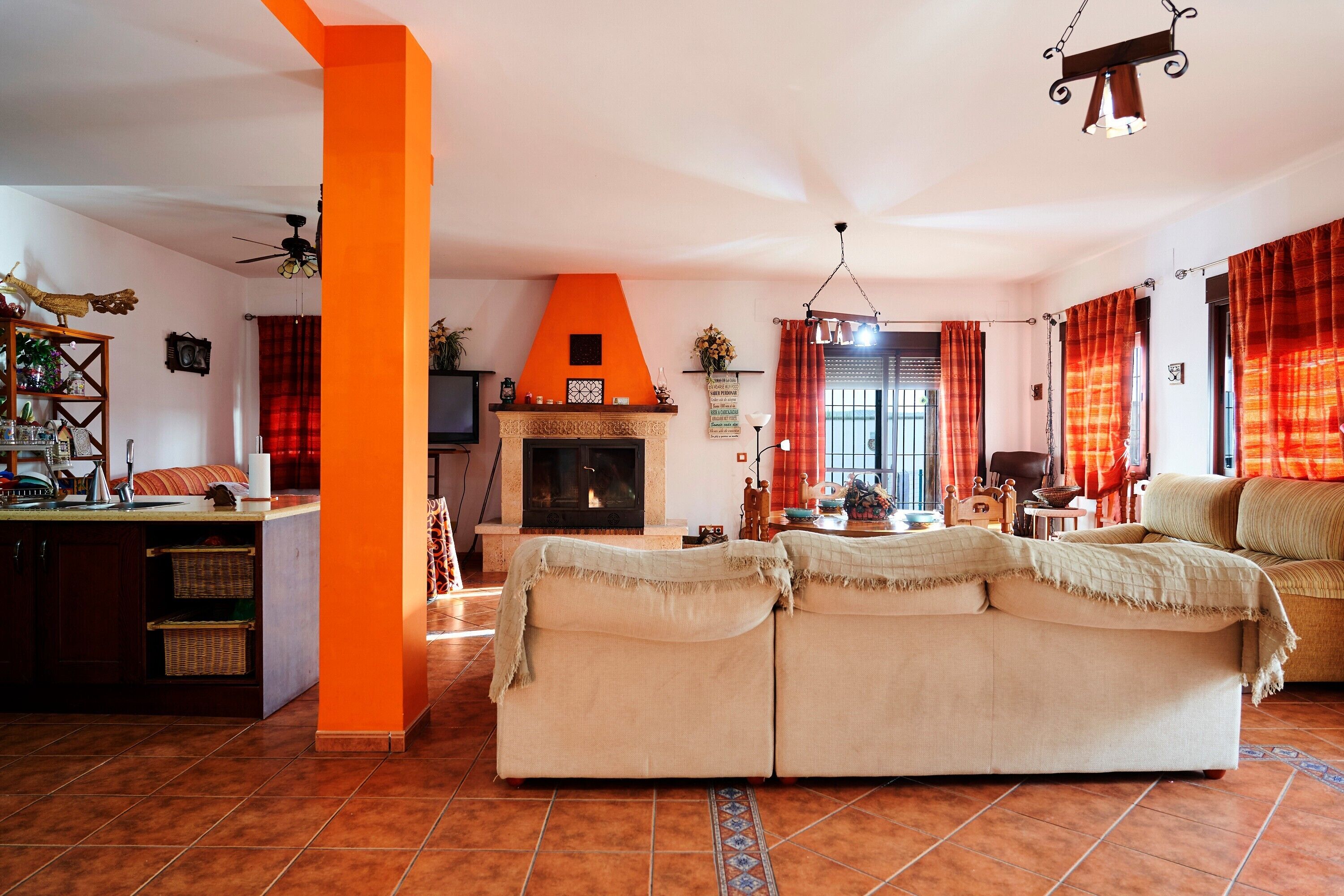 Una sala de estar con chimenea, sofá y una zona de cocina con mostrador.