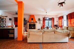 Una sala de estar con chimenea, sofá y una zona de cocina con mostrador.