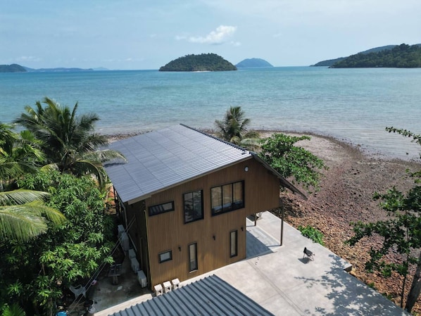 A modern building with a flat roof, large windows, and a concrete patio area. - Wave & Vibes Koh Chang (Ko Chang)
