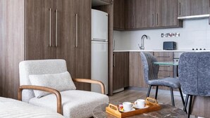 Una cocina moderna con armarios de madera, un refrigerador blanco y un comedor con una mesa de vidrio y dos sillas.