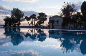 Ein Schwimmbecken mit klarem Wasser, das Bäume und ein Gebäude reflektiert.