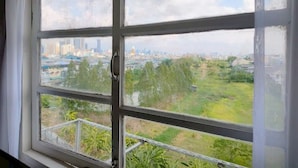 A window with a view of a cityscape and greenery. - Xin Hotel at Udomsuk 25 (Bangkok)