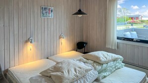 Una habitación con una cama, una ventana con vistas y una lámpara fijada a la pared.
