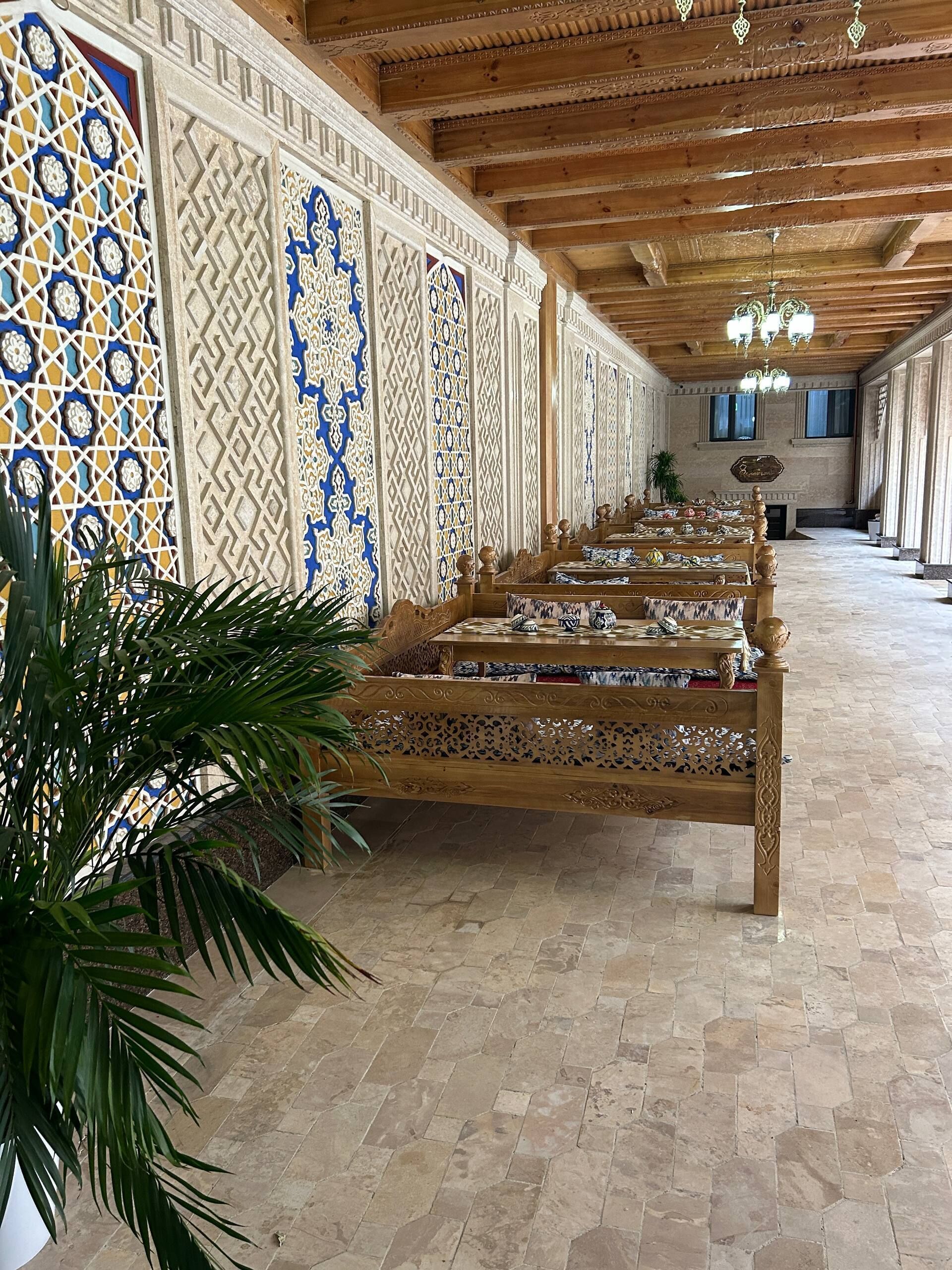 A long corridor with ornate wooden benches and patterned walls.