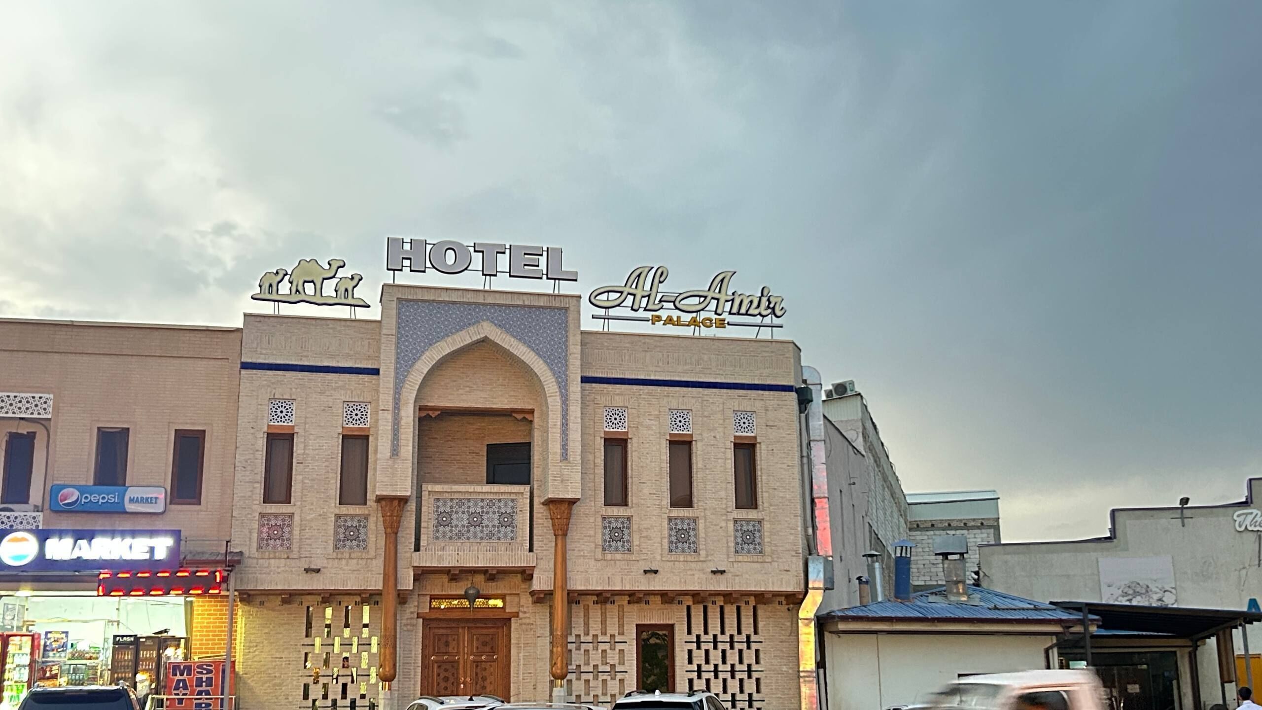 A hotel with a prominent sign, a market sign, and a Pepsi sign.