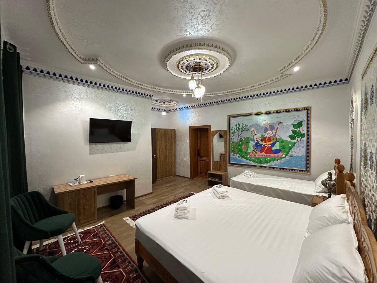 A hotel room with a large bed, a desk, a chair, a television, and a painting on the wall.