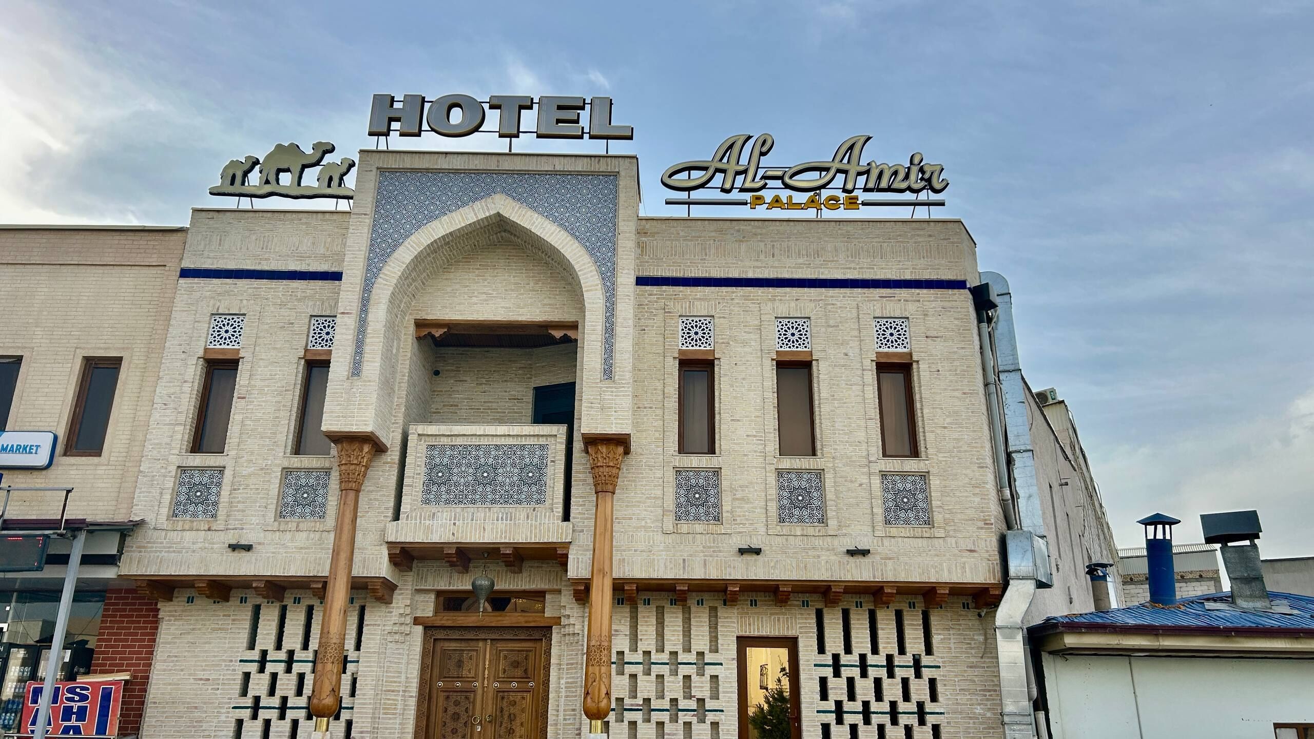 A hotel with a prominent sign, a central archway, and patterned tile work.