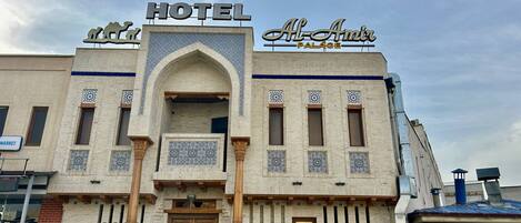 A hotel with a prominent sign, a central archway, and patterned tile work.
