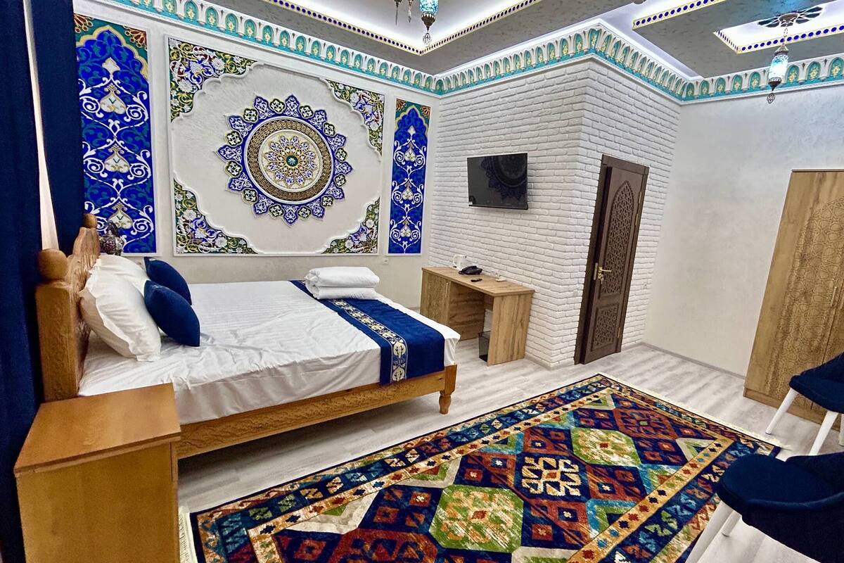 Quarto com cama, escrivaninha, cadeira, guarda-roupa e tapete estampado.