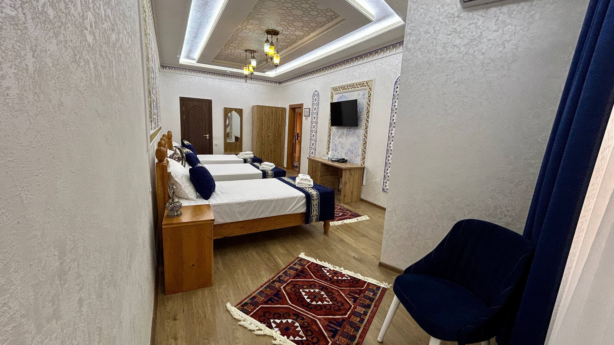 Una habitación de hotel con dos camas, televisor, escritorio y silla.