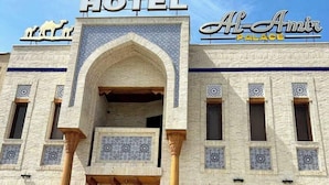 A building with a sign reading 'HOTEL' and 'Al-Amir Palace' above the entrance, featuring a traditional architectural style with arched doorways and patterned windows.