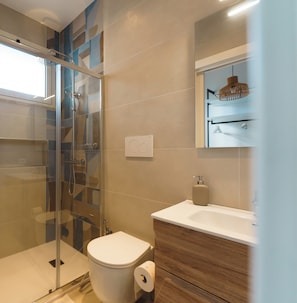 Ein modernes Badezimmer mit einer Duschkabine, einer Toilette und einem Waschbecken mit Holzunterschrank.