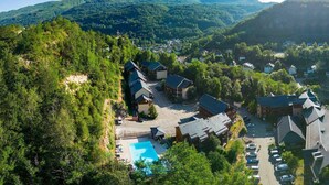 Un complexe hôtelier comprenant plusieurs bâtiments, une piscine et un paysage montagneux en toile de fond.