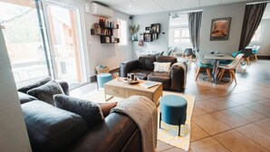 En moderne stue med sofa, sofabord og spiseområde med stole og bord.