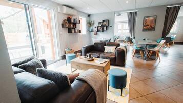 A modern living room with a sofa, coffee table, and a dining area with chairs and a table.