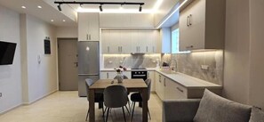 Una cocina moderna con comedor, horno empotrado y sofá gris.