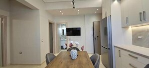 Eine moderne Küche mit einem Holzespeisetisch, integrierten Geräten und einem Flachbildfernseher.