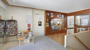 Et område med reception, et træbord ved receptionen, en opslagstavle med diverse meddelelser og en trappe, der fører til et øvre niveau.