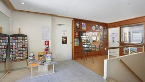 Et receptionsområde med en træreception, en opslagstavle med diverse informationer og en udstilling af rejsebrochurer.
