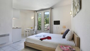 Et hotelværelse med seng, skrivebord, stol, tv og en balkon med udsigt.