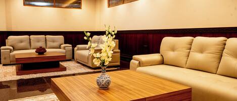 A modern living room with leather sofas, a wooden coffee table, and a vase of flowers.