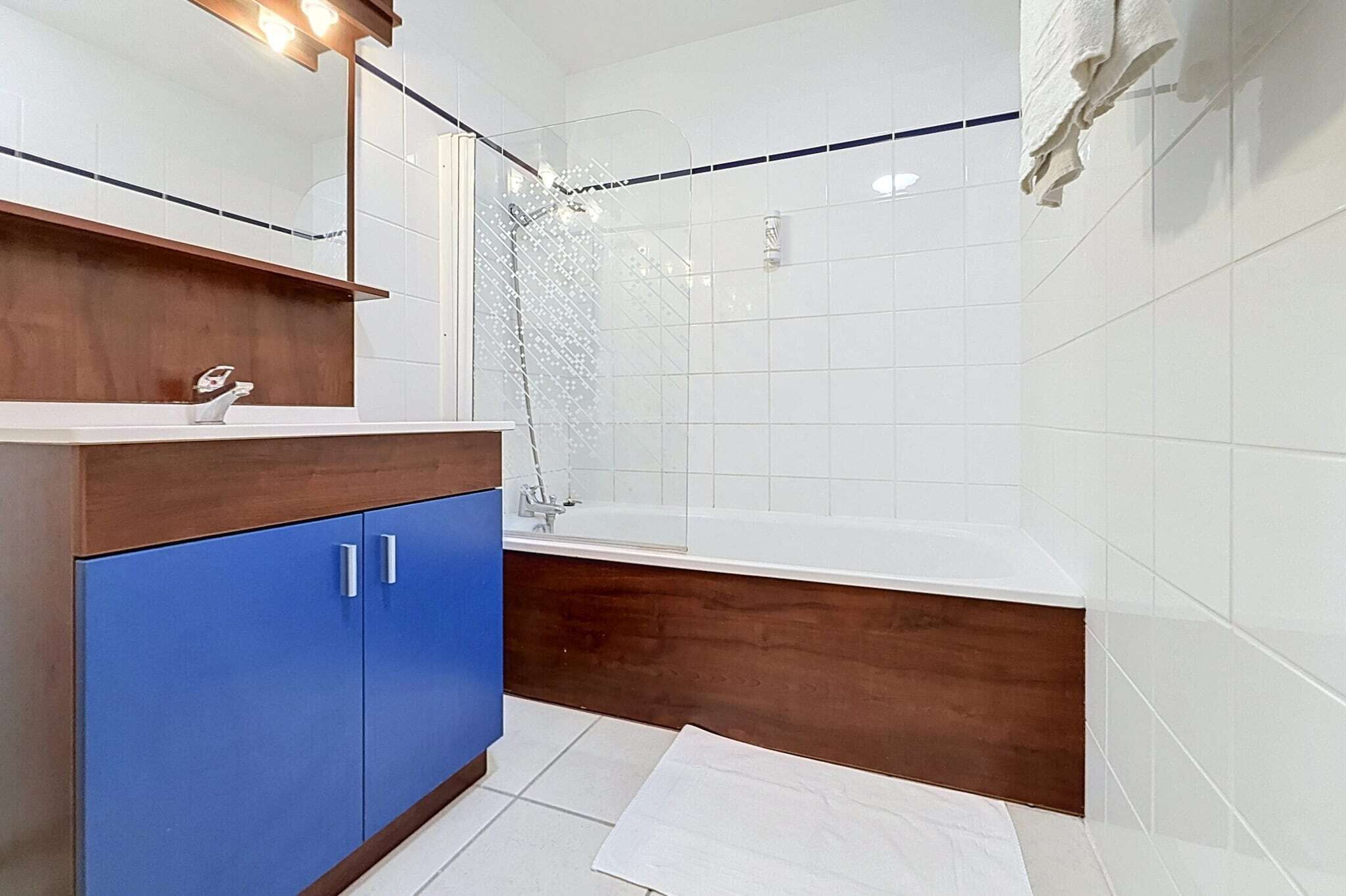 Ein Badezimmer mit einer Badewanne, einem Waschbecken mit Spiegel und einem Holzschrank.