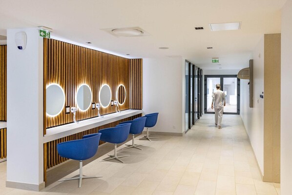 Een modern receptiegedeelte met een wand van houten panelen, een receptiebalie en blauwe stoelen.