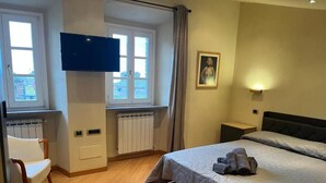 A bedroom with a bed, a chair, a TV, a radiator, and a window. - Prestigious penthouse in Maffei Palace, in the very center of Volterra (Volterra)
