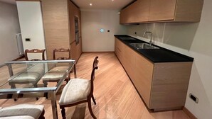 A modern kitchen with wooden cabinets, a black countertop, and a glass dining table with chairs. - Prestigious penthouse in Maffei Palace, in the very center of Volterra (Volterra)