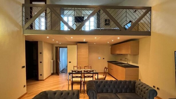 A loft-style apartment with a dining area, kitchen, and two grey sofas. - Prestigious penthouse in Maffei Palace, in the very center of Volterra (Volterra)