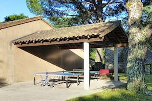 A covered outdoor area with a ping pong table and benches. - Mezzanine Cottage Stay in Ardèche (Chambonas)
