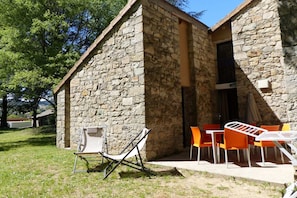 Un bâtiment en pierre doté d’un petit patio aménagé avec des sièges extérieurs.