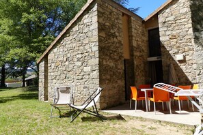 Un edificio de piedra con un pequeño patio y mobiliario exterior.